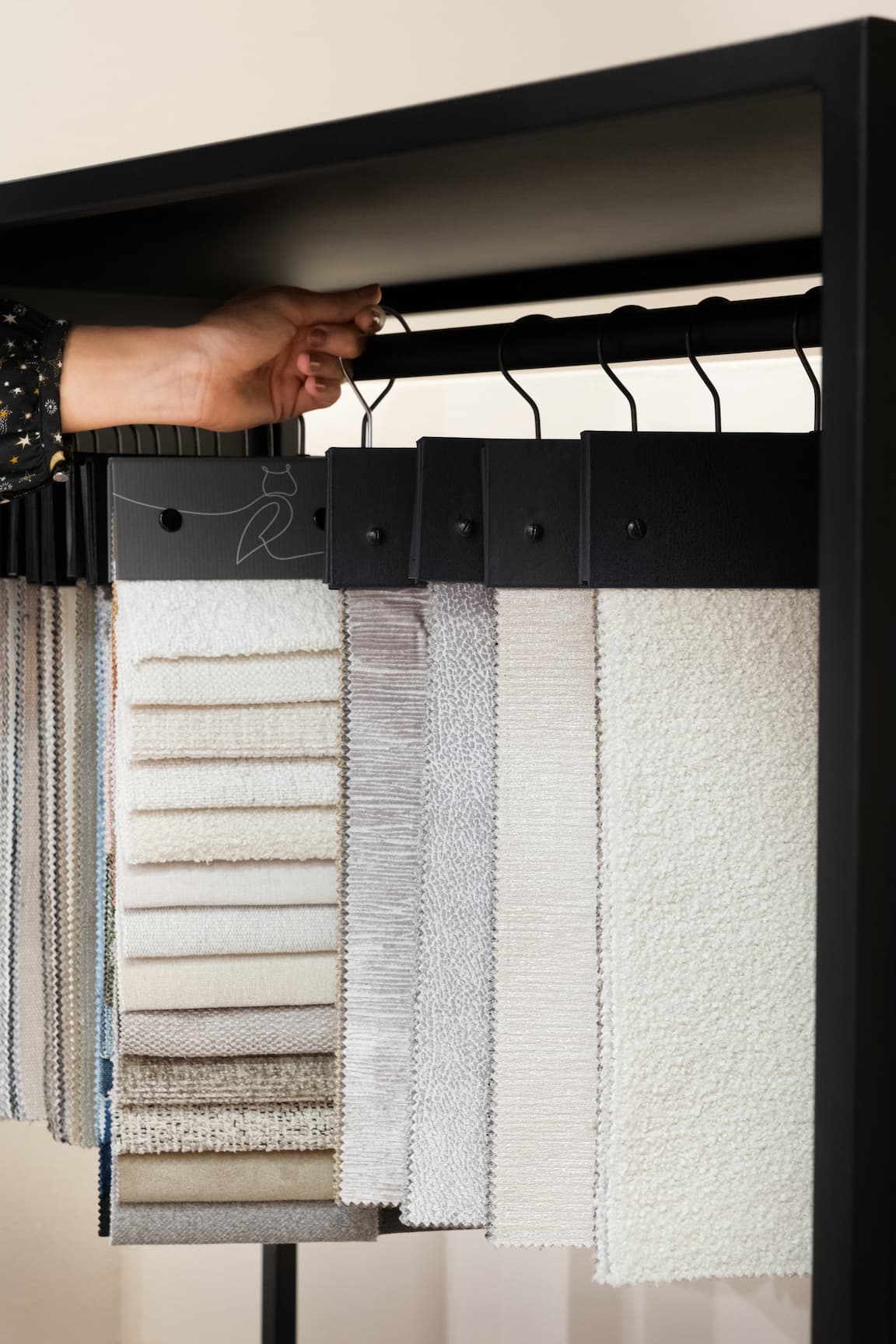 Échantillons de tissus pour literie suspendus, main sélectionnant un modèle