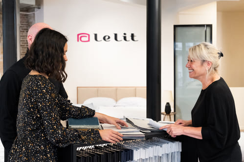 Personnes discutant de tissus dans un magasin "le lit", avec des échantillons sur le comptoir