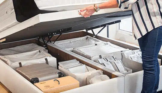 Lit coffre Mozart ouvert avec rangement organisé, valises et boîtes visibles