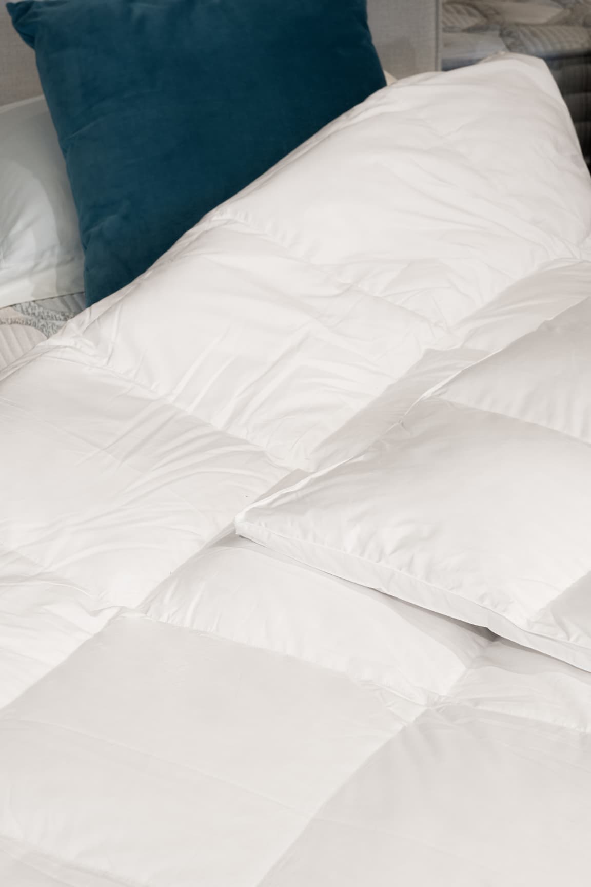 Couette blanche moelleuse sur un lit avec un coussin bleu en arrière-plan