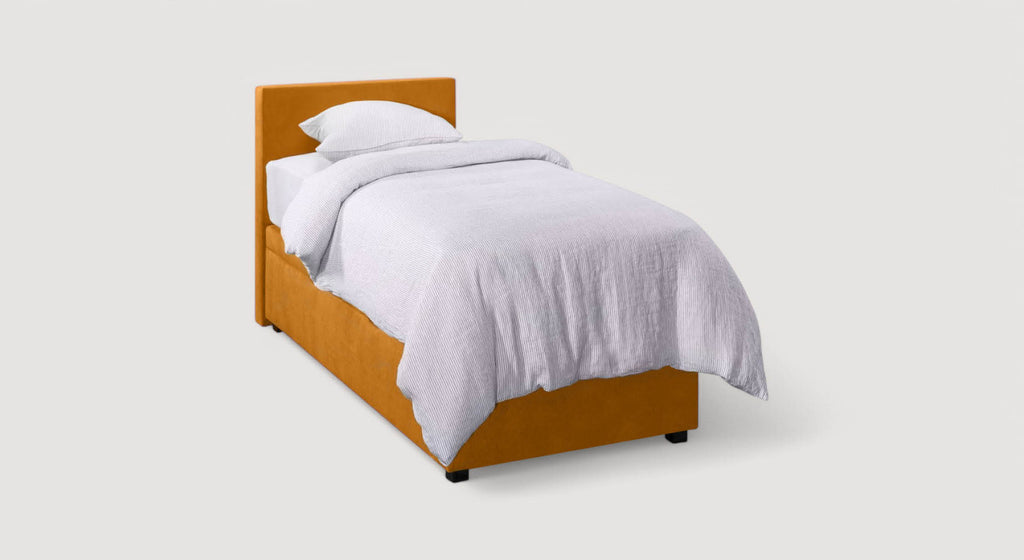 Lit coffre Ouessant en tissu orange avec matelas relevé, montrant un espace de rangement contenant des boîtes et une couverture