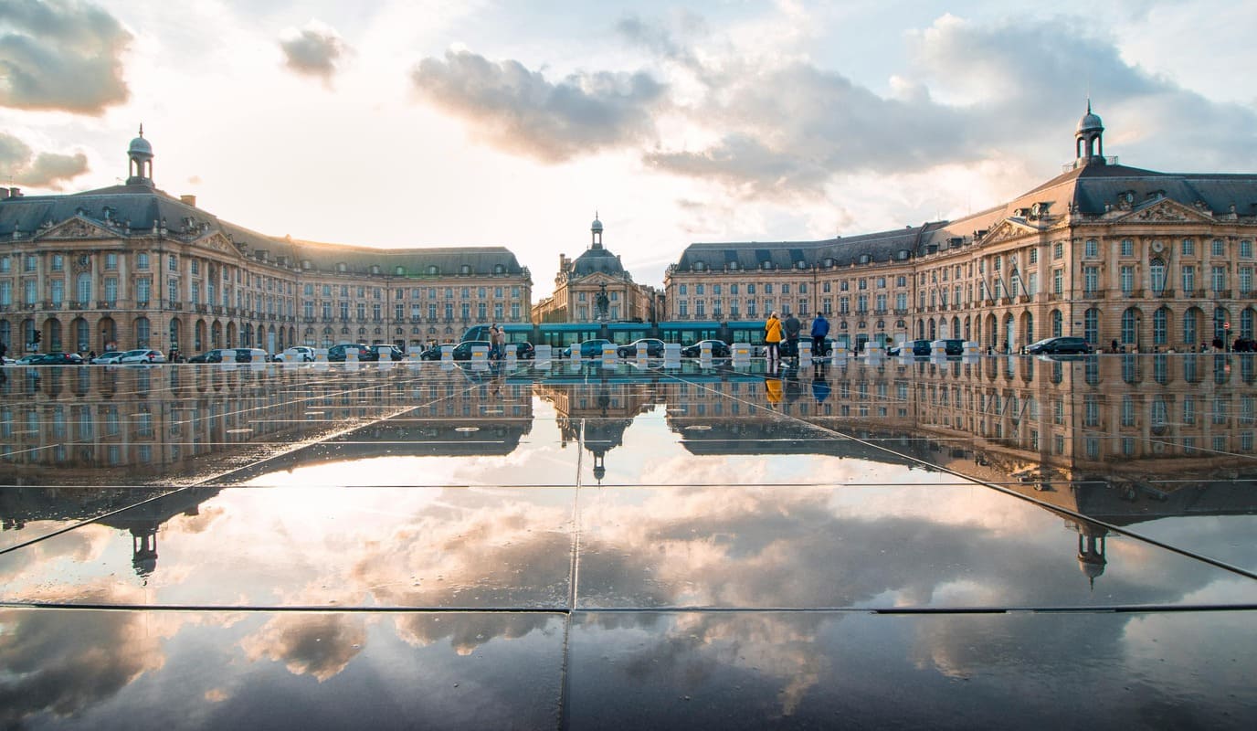 Place de la Bourse à Bordeaux avec reflet dans le miroir d'eau, ciel nuageux
