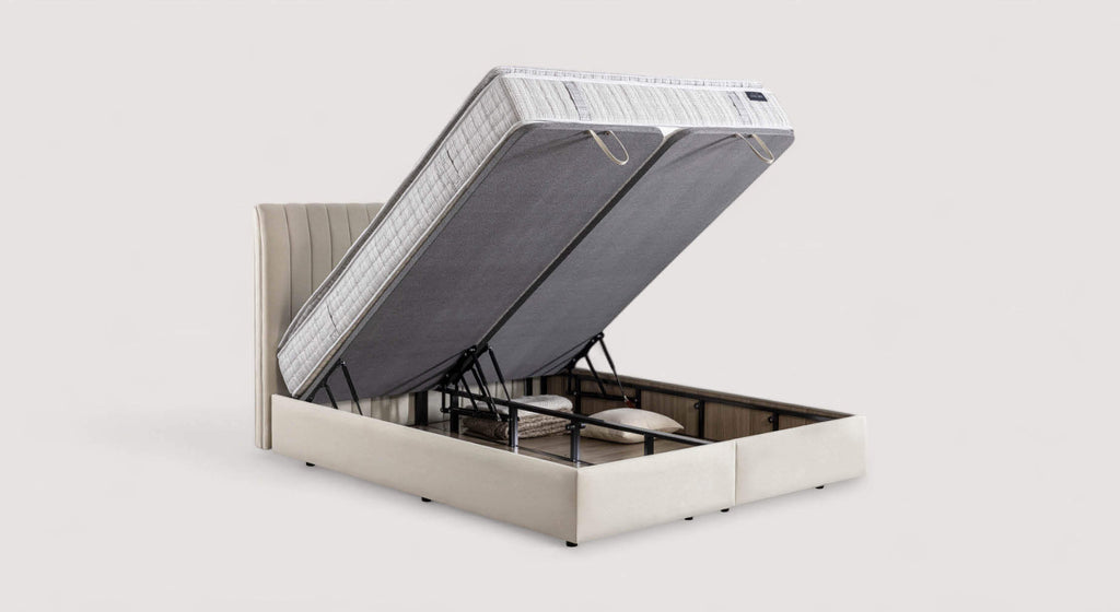 Lit coffre beige avec matelas relevé, montrant un espace de rangement contenant des oreillers et une couverture. Modèle Amsterdam