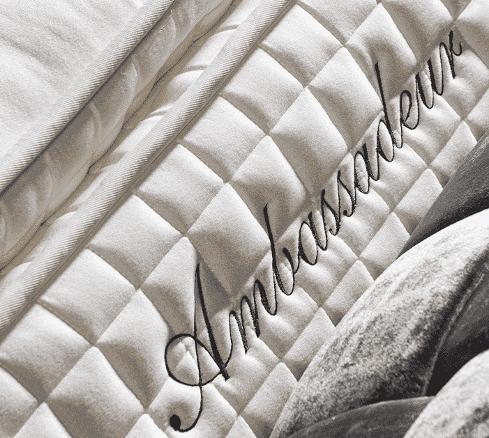 Matelas brodé "Ambassadeur" avec motif matelassé, évoquant luxe et confort, potentiellement lié à un événement de mariage