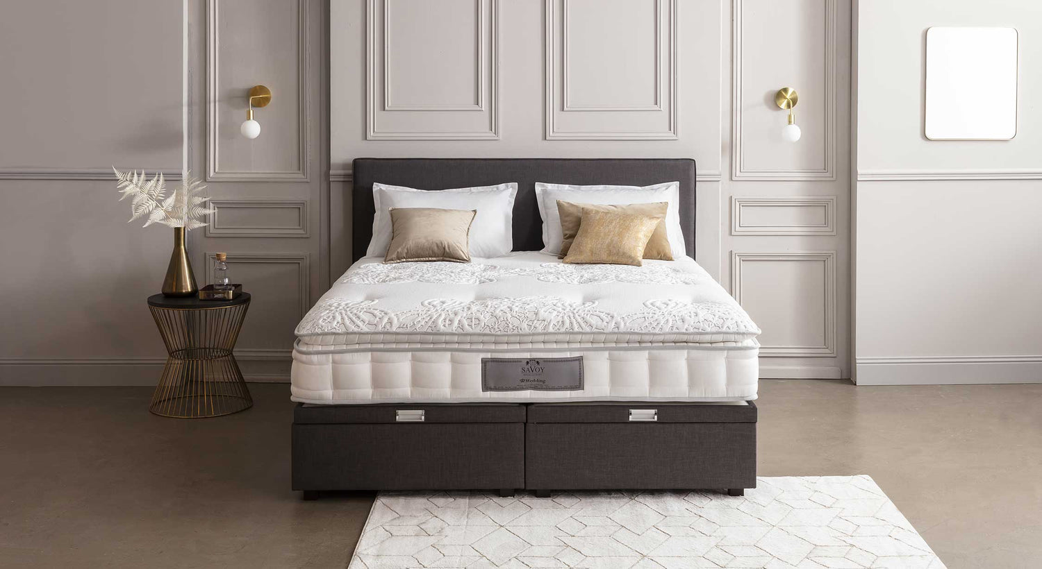 Lit élégant avec tête de lit Hilton, décoré de coussins dorés, dans une chambre au design raffiné avec table d'appoint et applique murale