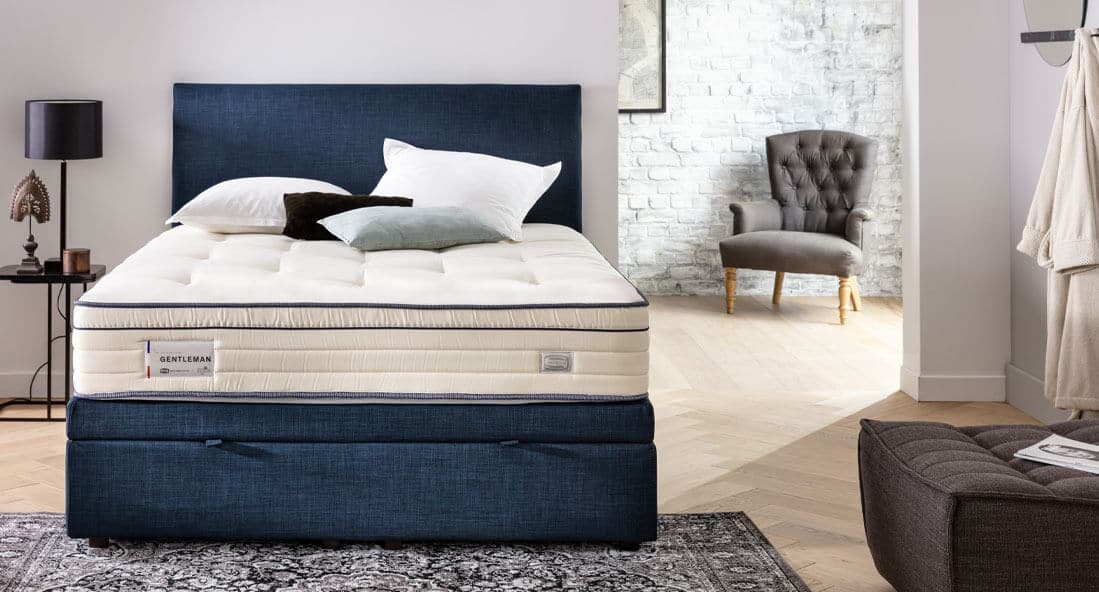 Lit avec matelas Simmons dans une chambre élégante, tête de lit bleue, coussins blancs et décor moderne