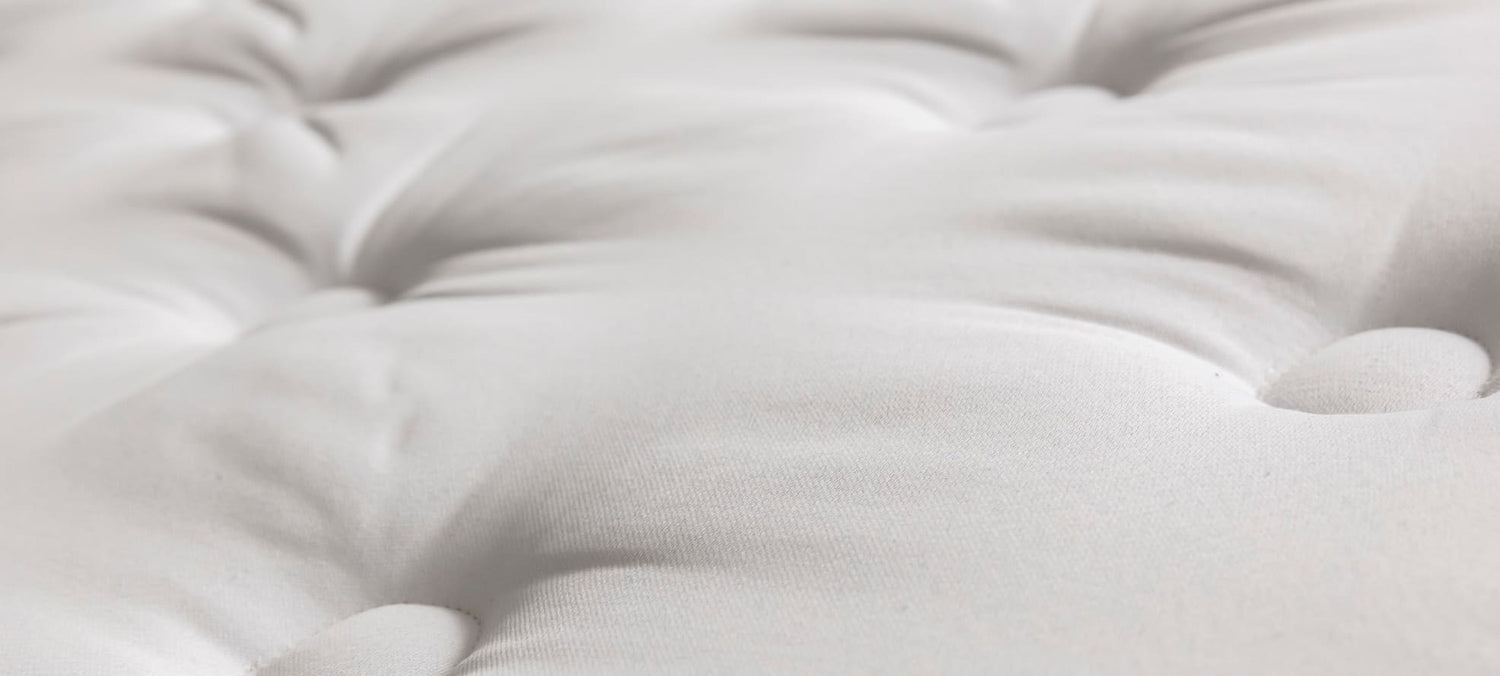 Surface matelassée blanche avec coutures, évoquant confort et douceur