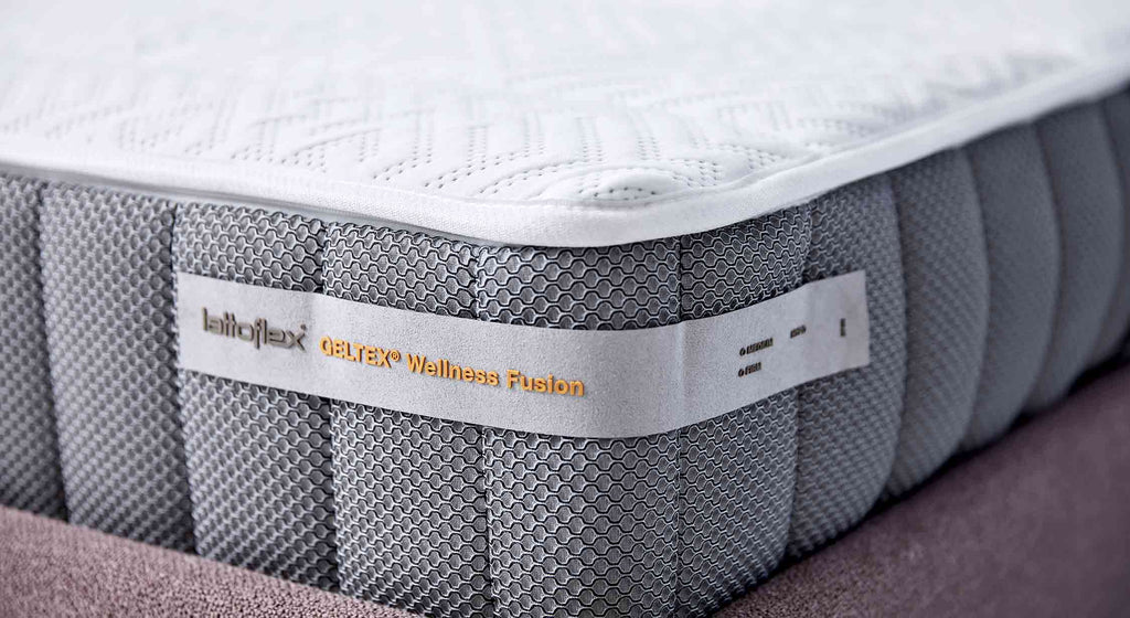 Matelas Geltex Wellness Fusion sur un lit bleu avec tête de lit, design moderne et élégant
