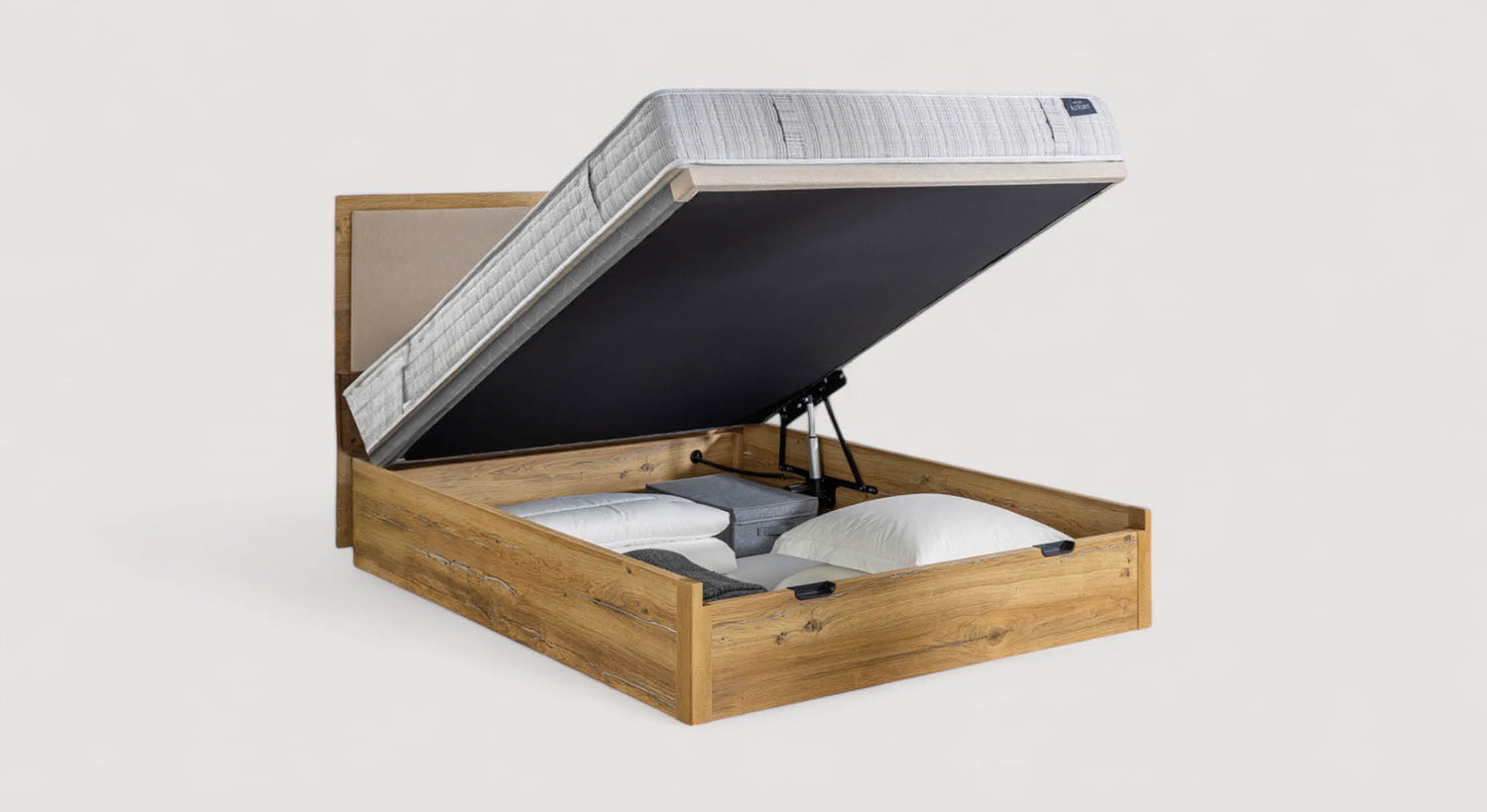 Lit coffre en bois avec matelas relevé, montrant un espace de rangement contenant des oreillers et des couvertures. Modèle Condor
