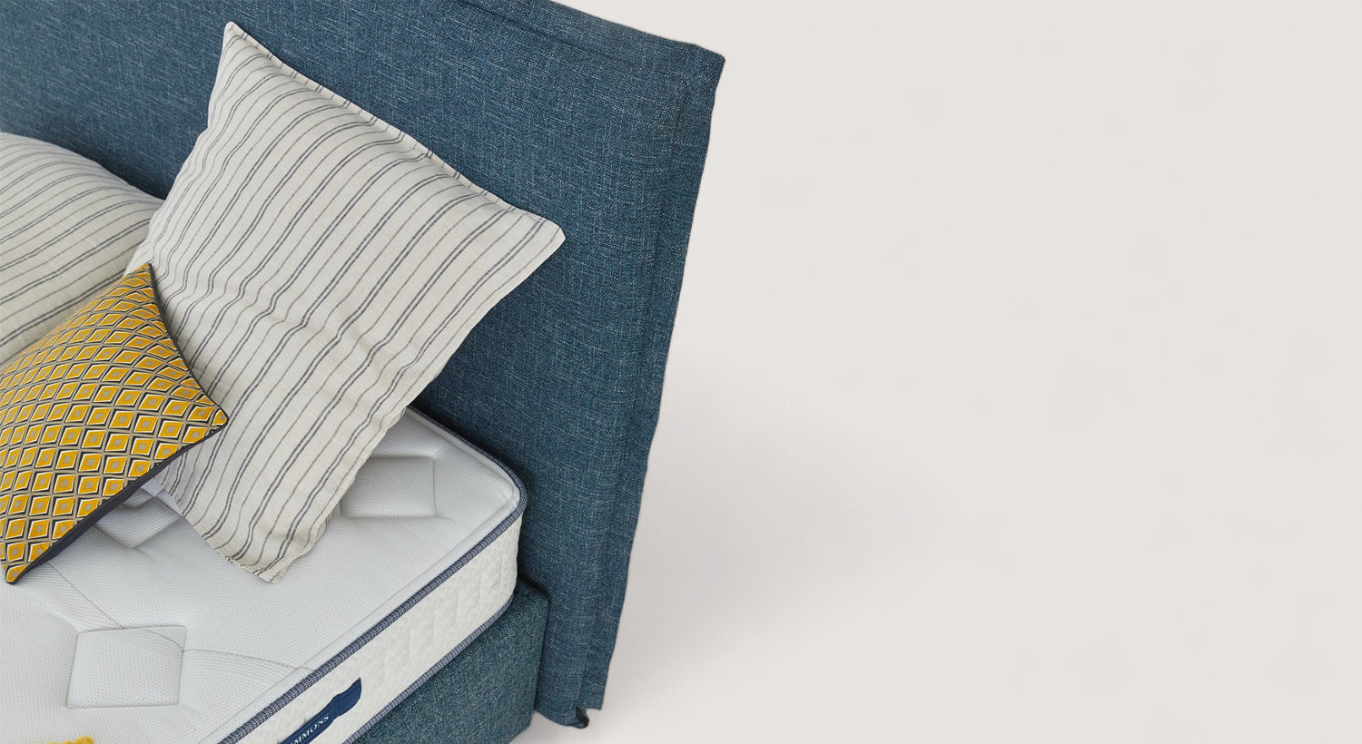 Tête de lit bleue Triana avec matelas blanc et coussins rayés et à motifs jaunes