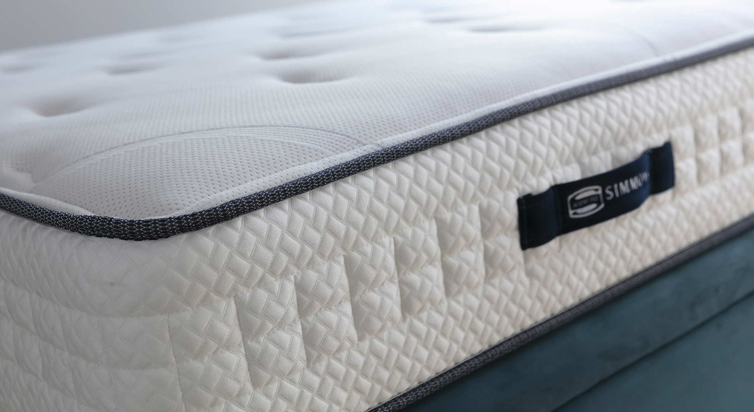 Matelas Simmons avec texture matelassée et bordure contrastante, évoquant une ambiance confortable et élégante