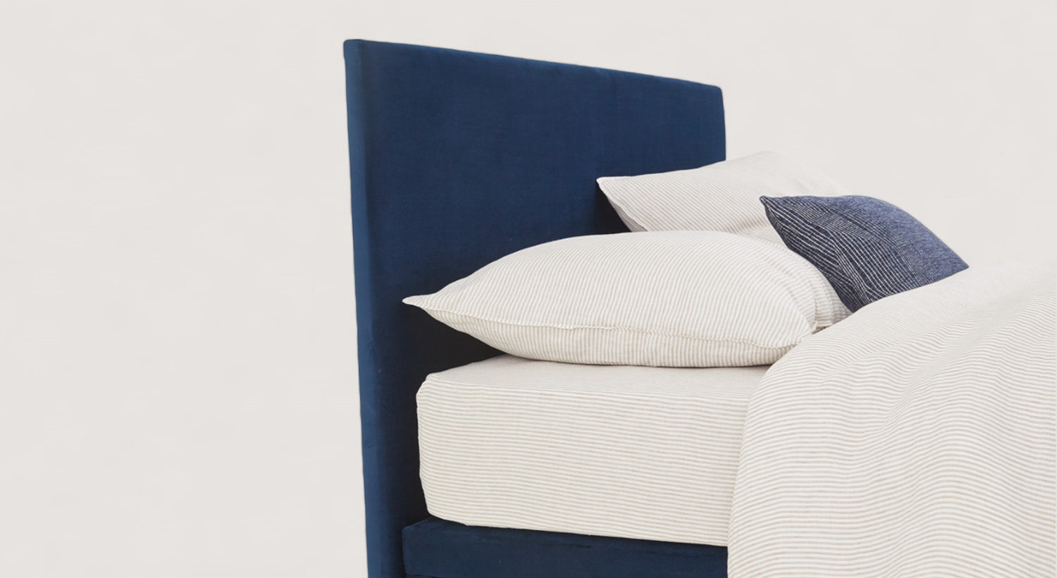Tête de lit bleu foncé avec literie rayée beige et coussin bleu, packshot du modèle Street 2