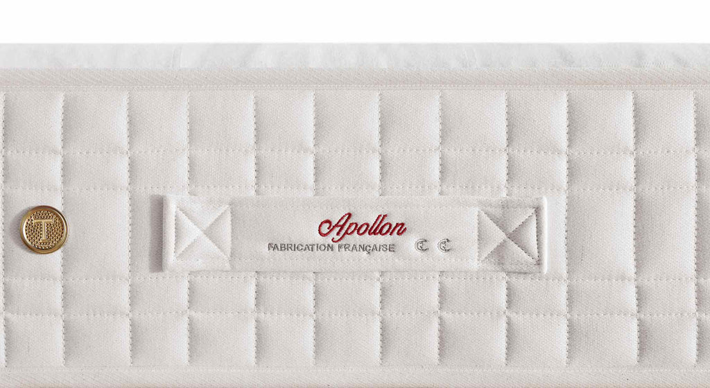 Matelas Treca Apollon avec coutures matelassées et étiquette visible, sur un sommier beige