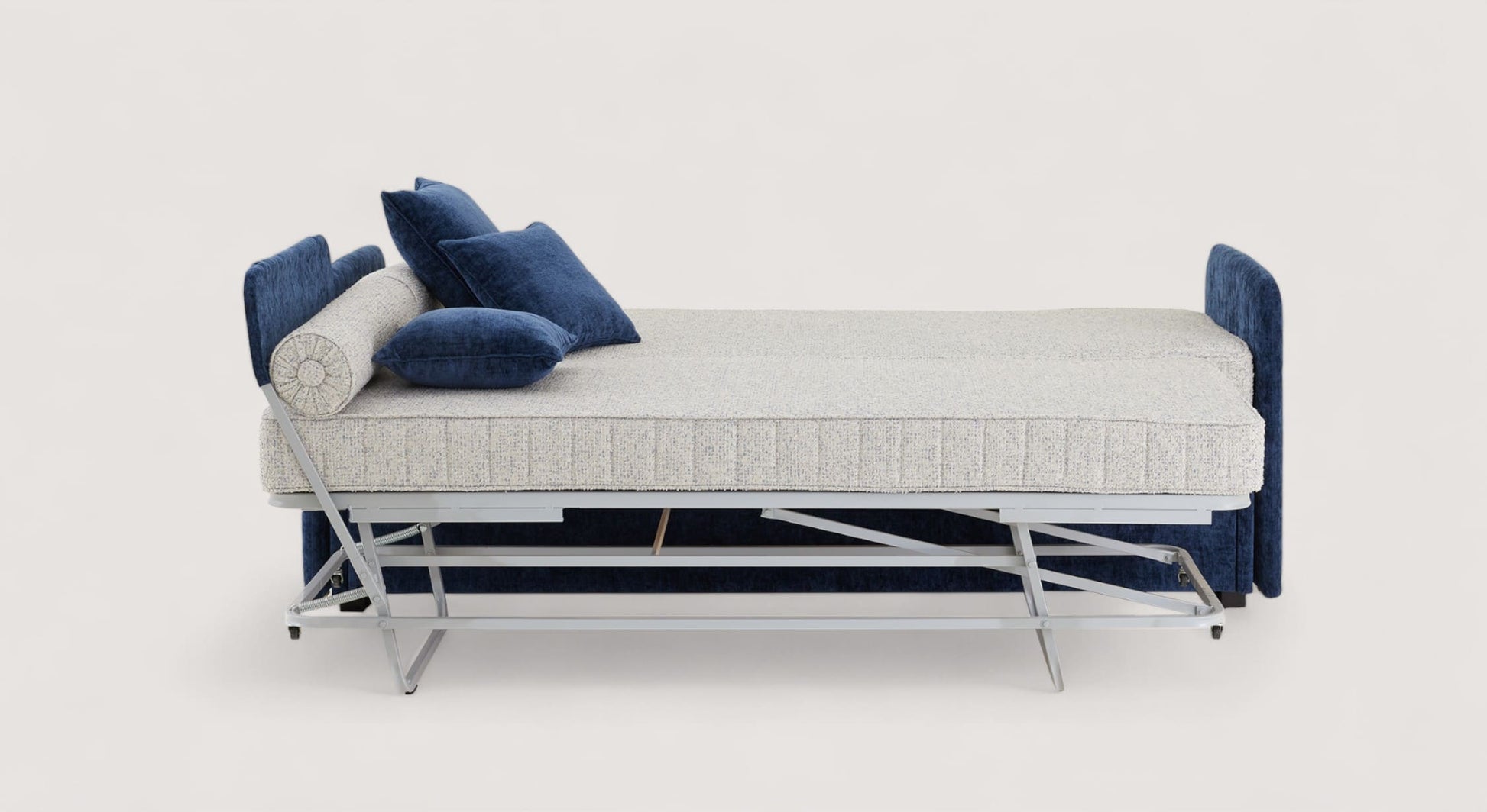 Lit gigogne Kilian avec structure métallique, matelas beige et coussins bleus, en position dépliée